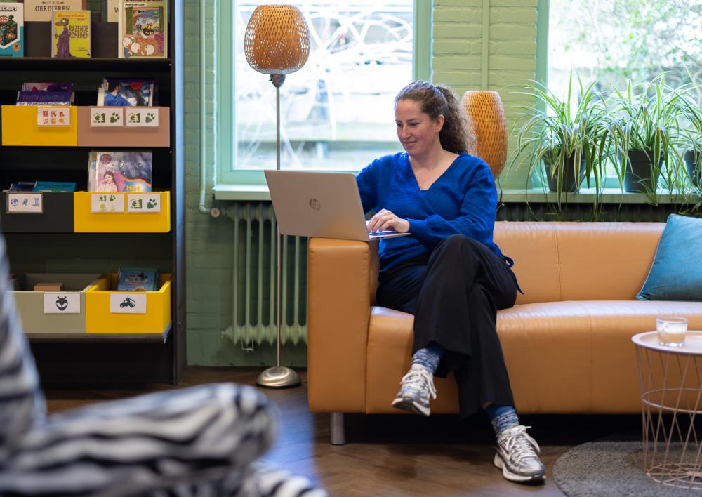Dame zit op computer op de bank bij de bibliotheek